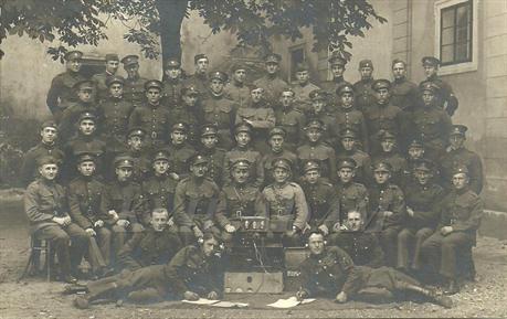 Skupinová fotografie vojáků spojovací čety pořízená v roce 1923 v kasárnách v Hradci Králové. Malý přístroj se třemi elektronkami je zesilovač typu 3-ter, který bylo možné používat jako příjímače zemního telegrafu.